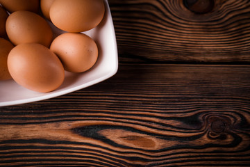Detail close-up of chicken eggs on the old brown wooden background.