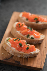 Bruschettas with salmon and cream cheese on olive wood board