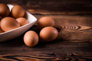 Detail close-up of chicken eggs on the old brown wooden background.