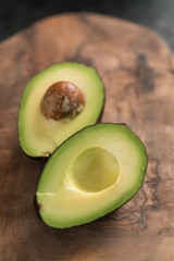 Ripe avocado sliced in halves on olive wood board closeup