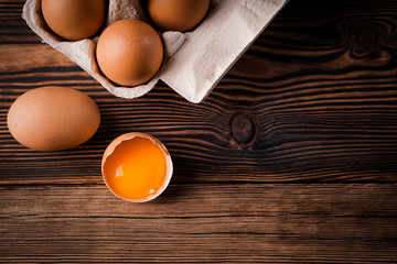 Detail close-up of chicken eggs in egg box on the old brown wooden background.