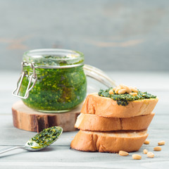 Close up view of baguette bread with fresh basil pesto sauce on gray wooden table. Copy space.