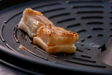 Grilled pork piece on hot pan for cooking food in party, roast pork meat and smoke from hot metal pan burning it, cooking menu show tasty and delicious food menu of meal, close up view photo of food