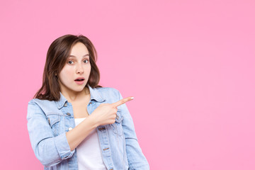 Pretty girl dressed in white t-shirt, denim jacket is standing on pink background. Young surprised...