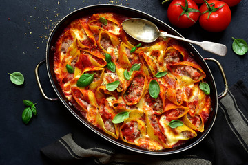 Stuffed pasta cannelloni with minced meat baked in  tomato sauce in a skillet. Top view with copy space.