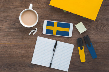 Swedish flag, textbook, smartphone, wireless headphones, foreign language learning concept 