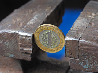 Coin one Turkish Lira clamped in a vise. The concept of financial and economic problems.