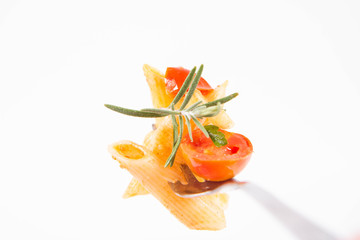 Penne with tomatoes, garlic and mozzarella on a fork decorated with rosemary twig on a white background