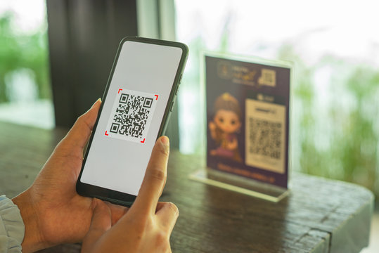 Woman scanning QR code from a label in a shop with mobile phone.
