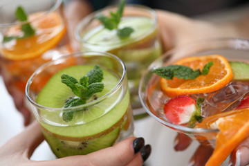 Hands holding glasses with cooling fruit cocktails