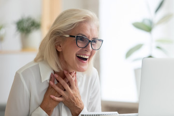 Surprised middle-aged businesswoman in glasses feel shocked read unexpected news online on laptop, stunned senior female employee feel amazed excited with pleasant email or message on computer
