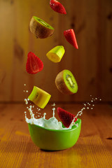 Splash milk with fruit flying and streeting on a wooden background