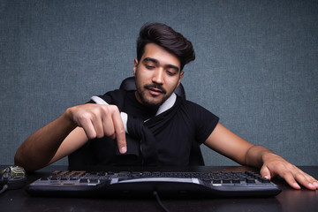 A young guy presses enter on the keyboard. on a gray background.