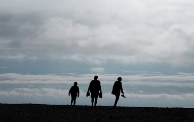 Family silhouettes walking to the beach, a slow restart of normal life after the pandemic.