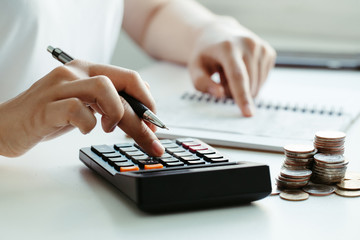 Tax concept.Woman hand using calculator and writing make note with calculate about cost at home...