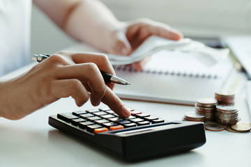 women calculate domestic bills at home. using calculator at modern office and checking balance and...