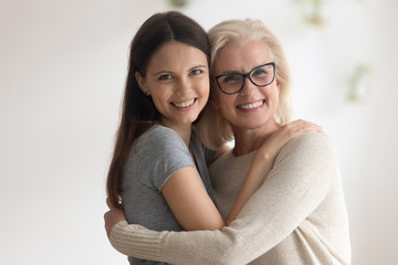 Portrait of smiling senior mother and adult daughter embrace show gratitude and love, happy caring mature mom and grownup millennial girl child hug look at camera posing, good relations concept