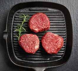 Raw beef fillet steaks on black iron pan top view