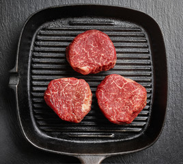 Raw beef fillet steaks on black iron pan top view