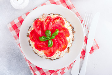 Festive layered salad with fried champignons, smoked chicken, eggs and cheese, garnished with fresh tomatoes, selective focus