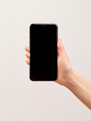 A modern smartphone with a large empty screen in the elegant hand of a girl on a white background.