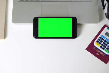 static mobile phone with a green screen booking flights with a passport and laptop online against a...