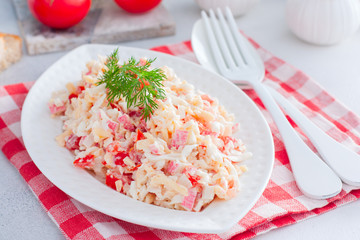 Homemade salad with crab sticks, tomatoes, cheese on a white dish, horizontal