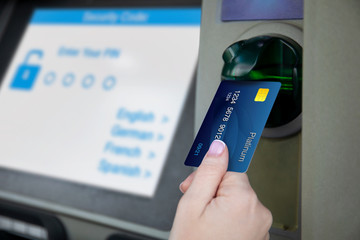 female hand holds credit card at ATM