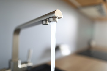 Close-up jet water from silver tap in kitchen