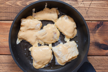 Step-by-step preparation of fried pollock fillet in batter, step 5 - frying in a pan frying pollock fillet in batter, top view, selective focus
