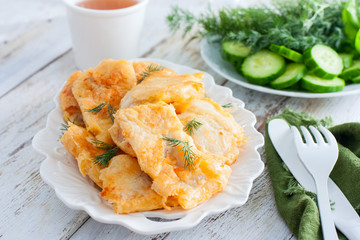 Pollock fillet in batter on a white plate, selective focus