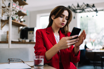 Young woman using mobile phone in cozy cafe