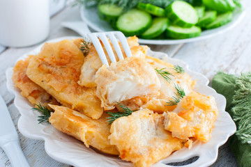 Pollock fillet in batter on a white plate, selective focus