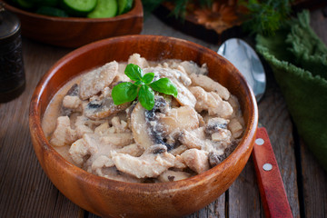 Stroganoff with chicken and mushrooms in a wooden bowl, selective focus