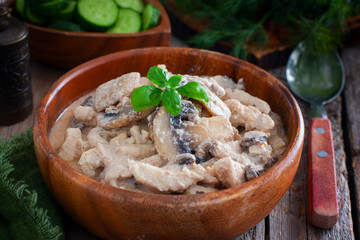 Stroganoff with chicken and mushrooms in a wooden bowl, selective focus