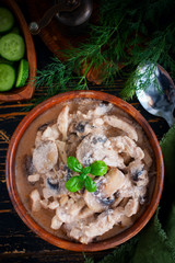 Stroganoff with chicken and mushrooms in a wooden bowl, selective focus