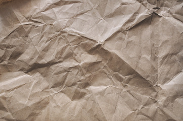 Background from crumpled light brown wrapping vintage paper. The texture of cardboard made from recycled materials.