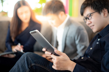 Asian businessman using digital tablet while discussing business plan with colleagues in meeting room. Smart portable device for conference in office. Modern working lifestyle concept