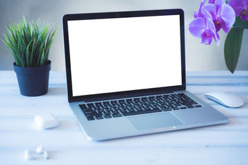 Fototapeta premium Laptop computer white blank screen on work table front view. Copy space, home and office workspace concept, laptop mockup.