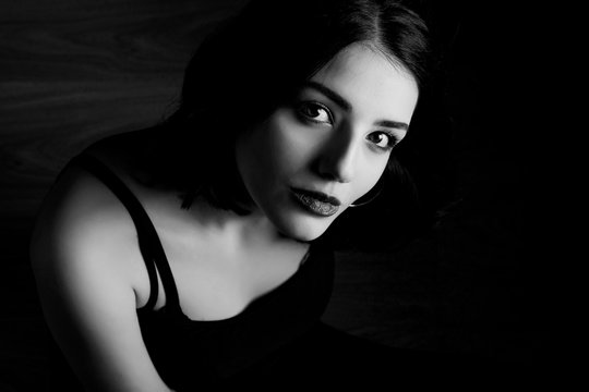 Black and white young woman looking at camera isolated on black background. Beautiful woman portrait.