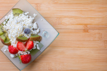 Cottage cheese with fresh summer berries in a bowl, top view of the table. Healthy dairy product rich in calcium and protein homemade milk.