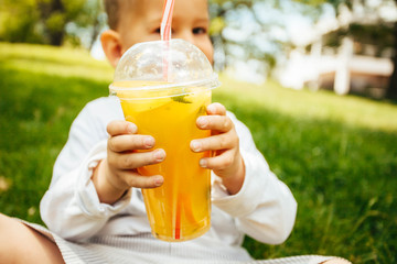 Little funny boy drinking a fresh  lemonade through a straw