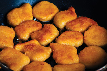 Chicken nuggets fried in a pan with butter