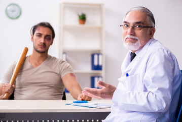 Fototapeta premium Young face injured man visiting experienced male doctor traumato