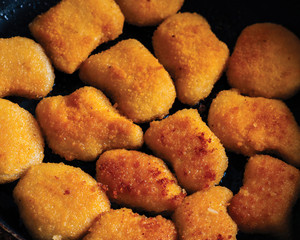 Chicken nuggets fried in a pan with butter