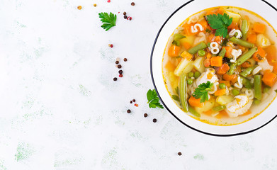 Minestrone, italian vegetable soup with pasta on light table. Top view, flat lay, copy space