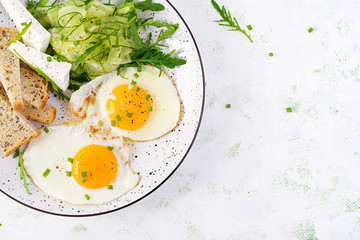 English breakfast - fried eggs, feta cheese, cucumber and arugula. American food. Top view, overhead, copy space