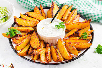 Baked potatoes with smoked paprika and sauce on a light background.