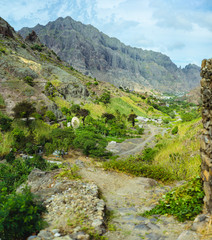 Palm trees in front of arid rocky terrain. Huge barren mountain in background. Santo Antao Island,...