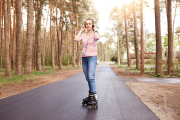Portrait of confident sporty energetic young female listening to music, putting on headphones,...